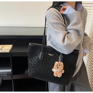 Detail of leopard print tote bag with gold brand logo and cute plush bear charm