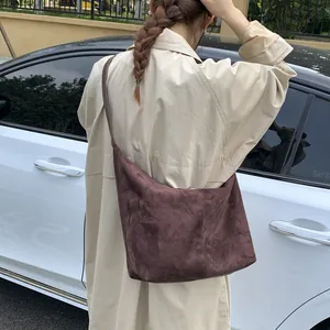 Grand sac hobo en daim marron porté par un mannequin pour un look décontracté chic