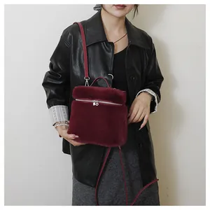 Detail van een pluizige bordeauxrode handtas met handvat en crossbody riem voor dames