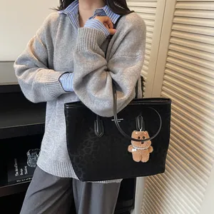 Black leopard print tote bag with plush bear charm and long leather handles