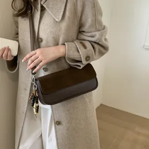 Brown suede crossbody bag with wooden bead charm paired with cream wool coat