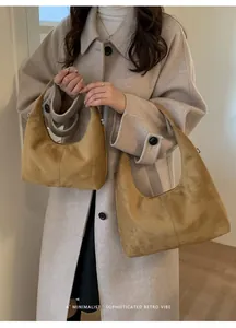 Minimalist mustard yellow suede hobo bags in two sizes worn with a beige winter coat