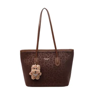 Brown leopard print tote bag with plush bear charm and spacious shoulder straps