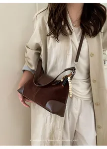 Close-up of minimalist dark brown suede and leather crossbody bag with colorful bead charm