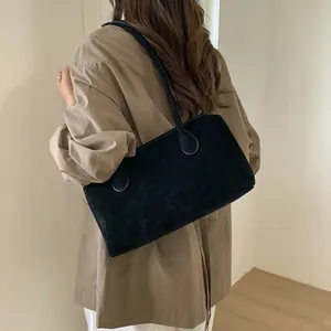 Minimalist large black suede tote bag with slim shoulder straps shown on a model