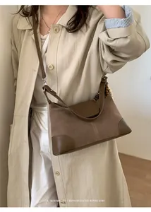 Close-up of brown suede and leather patchwork crossbody bag with retro wooden bead charm