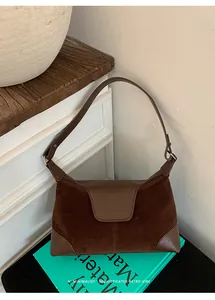 Detail view of deep brown suede and leather splicing on a vintage crossbody bag