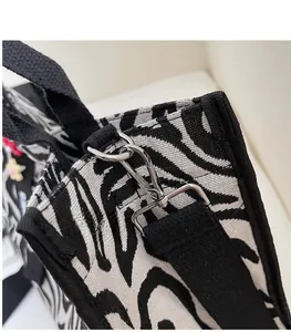 Close-up of durable silver metal swivel hook and black strap on zebra canvas bag