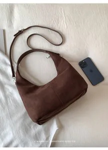 Close-up of deep brown suede hobo bag with vertical stitching and silver hardware