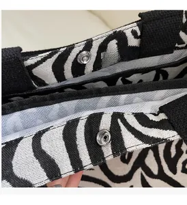 Detailed view of striped canvas tote bag featuring metal snap button and cotton straps