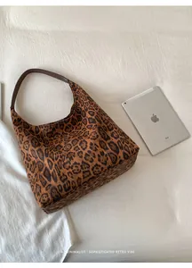 Detail of leopard print tote bag with brown leather strap on minimalist background