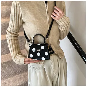 Detailed view of polka dot mini handbag with silver metal turn-lock and adjustable strap