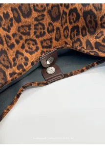 Macro detail of leopard faux fur bucket bag featuring brown leather trim and magnetic closure