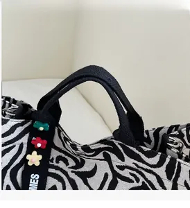 Detailed close-up of zebra stripe canvas bag handle with colorful 3D floral decorations