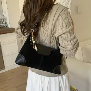Black suede patchwork crossbody bag with decorative wooden beads on a female model