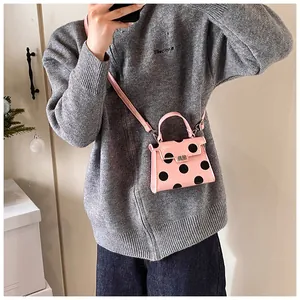 Close-up of pink polka dot mini crossbody bag with metal twist lock and shoulder strap