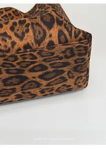 Close-up of leopard print handbag showing reinforced bottom stitching and suede texture