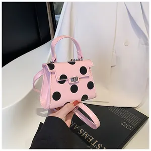 Detail of pink polka dot mini handbag with metallic twist lock and bow accent