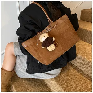 Detail of vintage brown suede tote bag with metal buckle and plush bear pendant detail