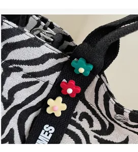 Detail of zebra pattern canvas bag featuring colorful 3D floral accents on the strap