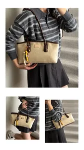 Close-up of retro beige tote bag with brown leather trim and wooden bead tassel detail