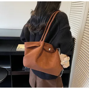 Vue détaillée d'un grand sac cabas en daim marron avec un pendentif ours en peluche et perles