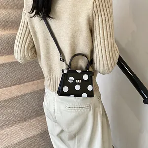 Structured mini trapezoid handbag with polka dots and metal lock shown on a model
