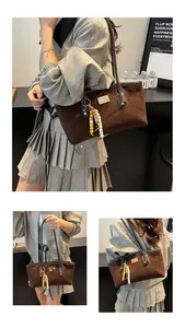 Close-up of brown suede tote bag featuring colorful beaded wooden charms and metal logo