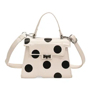 Chic beige polka dot crossbody bag with a unique cutout base and metal buckle closure