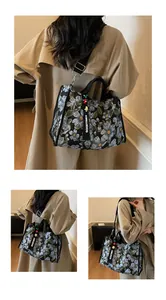 Detail of floral embroidery canvas tote bag with adjustable strap and designer pendant
