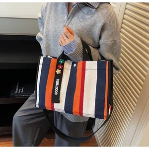 Detail of colorful striped canvas tote bag with GOODTIMES charm and floral accents