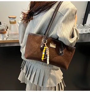 Detailed macro of dark brown suede tote bag with colorful ethnic beaded pendant