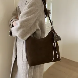 Brown matte suede tote bag with half-moon shape and decorative fringe pendant