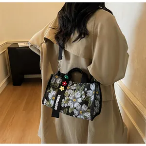 Detail of floral canvas tote bag with GOODTIMES strap worn by a model in beige coat