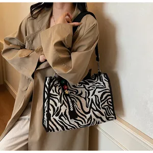 Detail of zebra pattern canvas tote bag with black strap and floral charm on trench coat