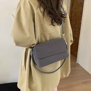 Dark grey faux suede crossbody bag with silver hardware on a tan trench coat outfit