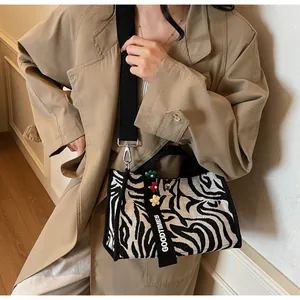 Detail of zebra stripe canvas tote bag with floral charm and adjustable strap