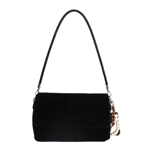 Minimalist black suede crossbody bag with flap closure and wooden bead pendant detail