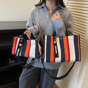 Striped canvas tote bag in navy and orange with adjustable shoulder strap and floral charm