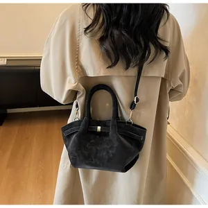 Détails d'un sac à main noir en daim avec boucles dorées et bandoulière ajustable