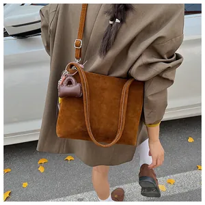 Borsa a tracolla in pelle scamosciata marrone con mini ciondolo e tracolla regolabile
