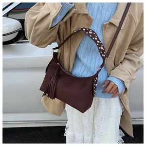 Detail of wide shoulder strap with rhinestones and long tassel on brown suede bag