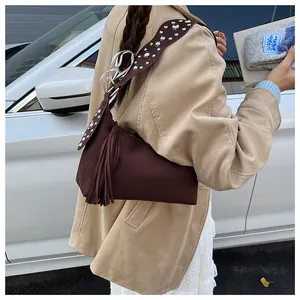 Detail of brown suede shoulder bag with metallic rivets and long fringe tassel accents
