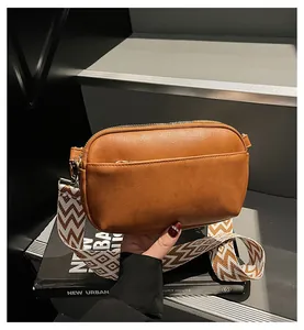 Bruine PU-leren crossbodytas met vintage geweven schouderband op modeblad gelegd