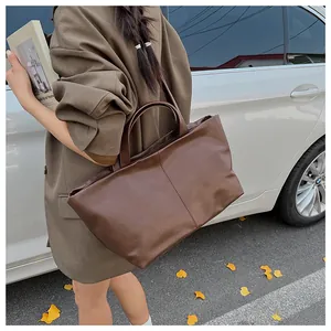 Detailed view of a brown leather tote bag held by a model in an elegant street setting