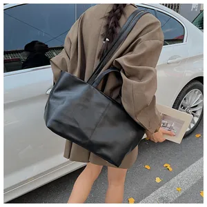 Detailed back view of a large black leather tote bag worn by a model in a city street setting