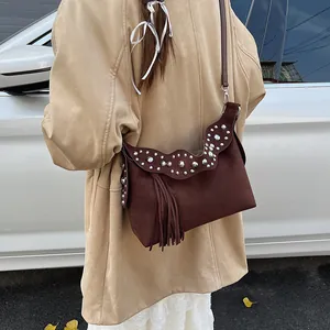 Vintage brown frosted leather hobo bag with fringe and silver studs in street style view