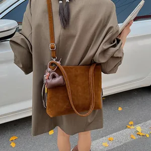 Borsa a spalla minimalista marrone opaco con mini ciondolo su strada autunnale