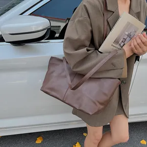 Deep brown leather tote bag for women featuring vertical stitching in an outdoor setting