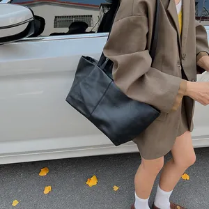 Minimalist black large capacity leather tote bag for women shown in an outdoor street setting